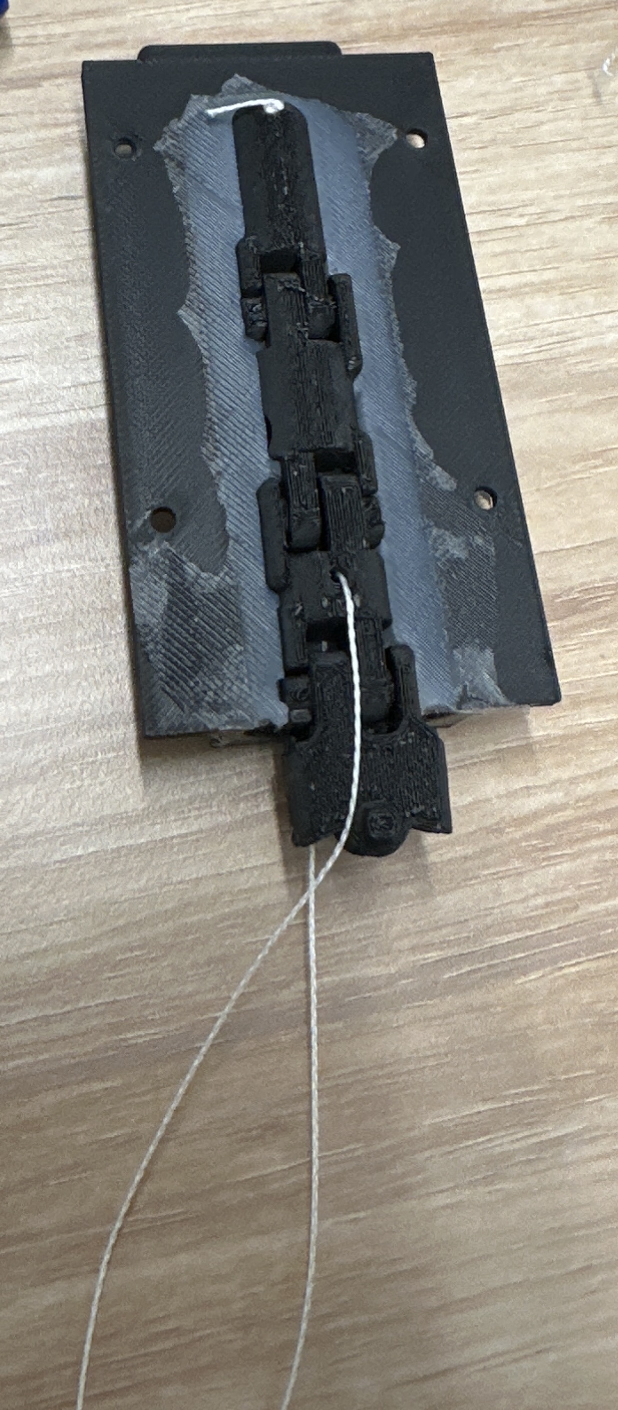 Articulated robotic finger joint chain positioned in a silicone mould with tendon lines attached